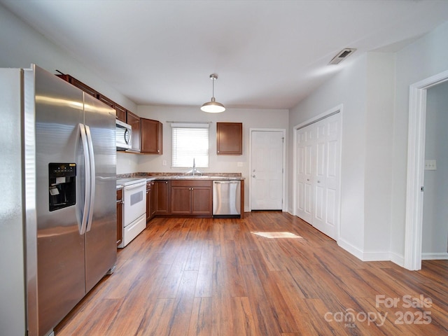 kitchen featuring hanging light fixtures, appliances with stainless steel finishes, dark wood-type flooring, and sink