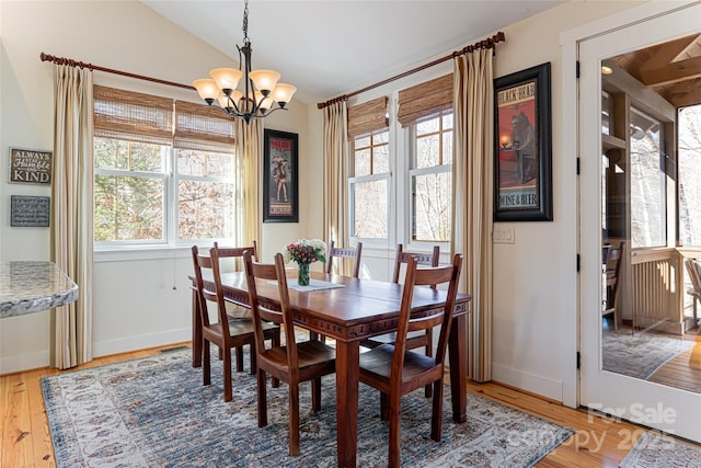 dining room featuring lofted ceiling, hardwood / wood-style floors, and a chandelier