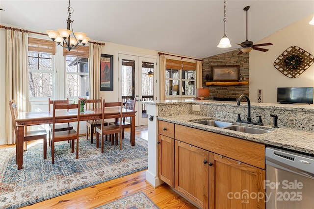 kitchen with dishwasher, sink, light stone countertops, and light hardwood / wood-style flooring