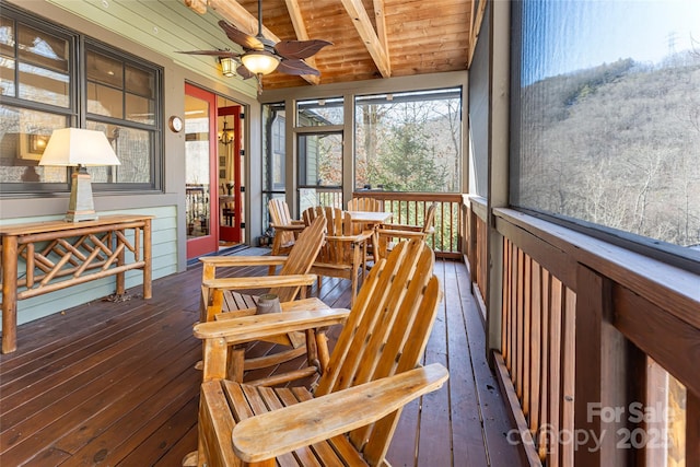 sunroom featuring beamed ceiling, ceiling fan, and wooden ceiling