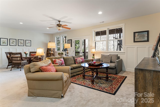 carpeted living room with ceiling fan and french doors