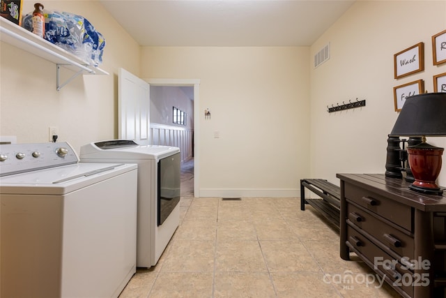 clothes washing area with washer and dryer and light tile patterned floors