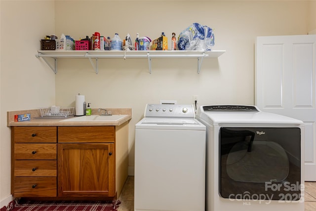 clothes washing area featuring separate washer and dryer, sink, and cabinets