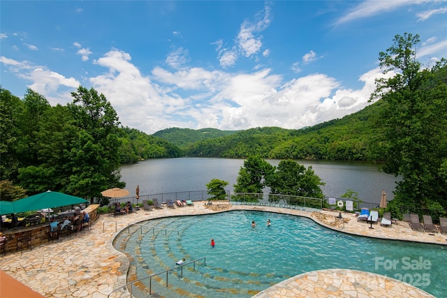 view of pool with a water view and a patio area