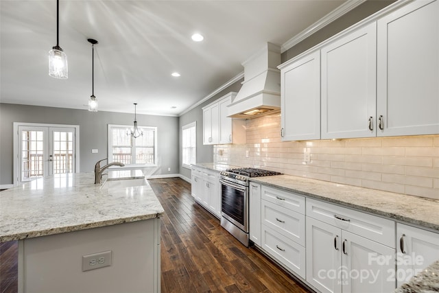 kitchen featuring hanging light fixtures, stainless steel range with gas stovetop, a center island with sink, and premium range hood