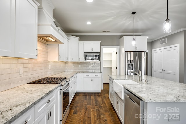 kitchen featuring a center island with sink, visible vents, hanging light fixtures, appliances with stainless steel finishes, and white cabinetry