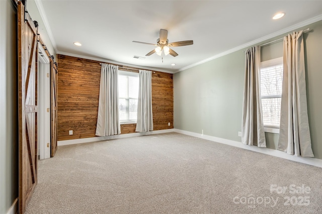 unfurnished room with visible vents, a barn door, ornamental molding, light carpet, and ceiling fan