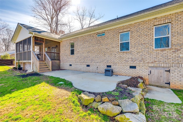 back of house with a lawn, a sunroom, crawl space, a patio area, and brick siding