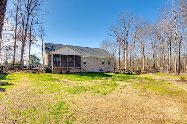 back of property featuring crawl space, a yard, a sunroom, and brick siding