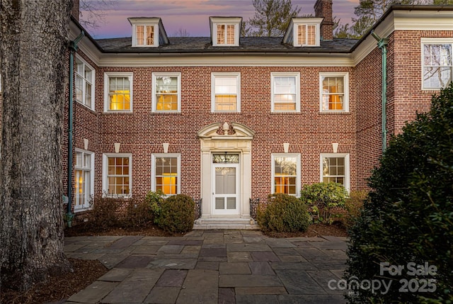 colonial-style house with a patio and brick siding