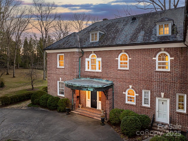 view of front of home with brick siding and a high end roof