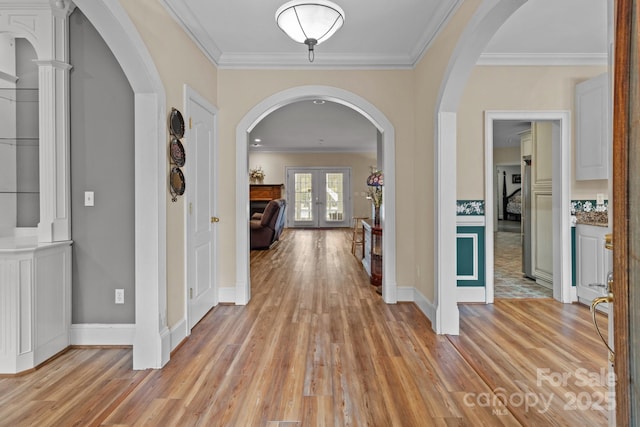 hallway with light wood-style floors, crown molding, and french doors