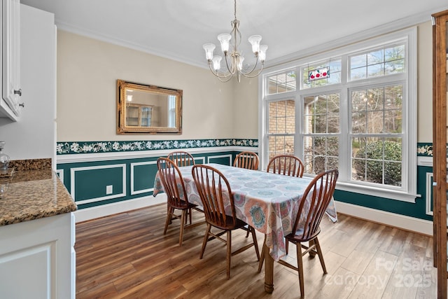 dining space with a wainscoted wall, ornamental molding, a wealth of natural light, and wood finished floors