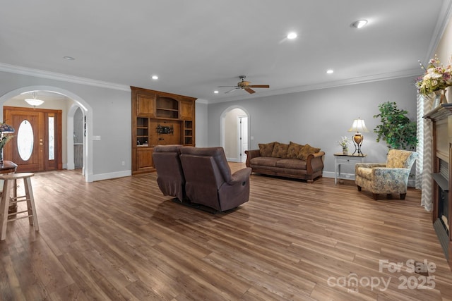 living room with arched walkways, a fireplace, wood finished floors, and recessed lighting