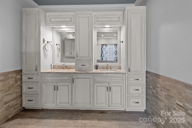 full bath with a wainscoted wall, tile walls, and a sink