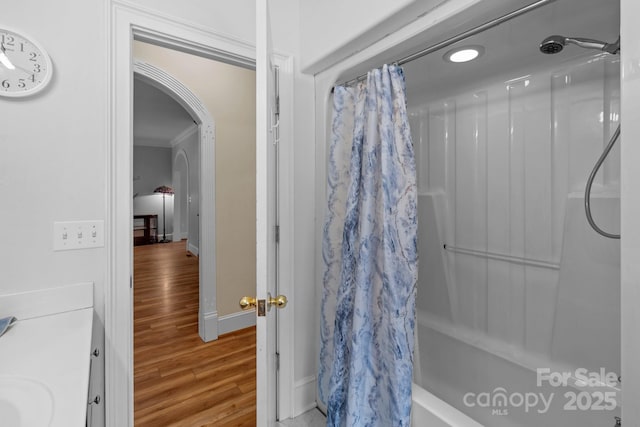 full bath featuring shower / tub combo, baseboards, ornamental molding, and wood finished floors