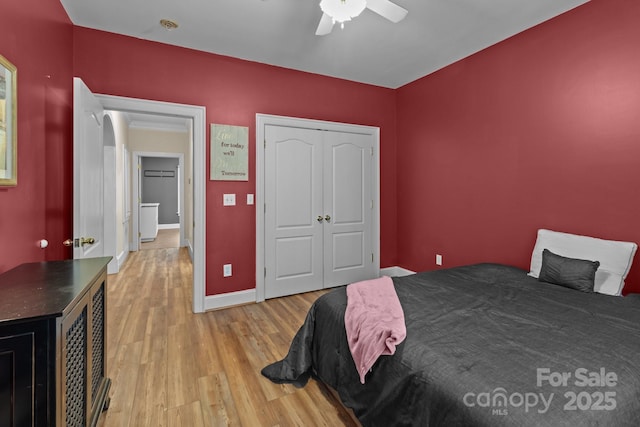 bedroom featuring ceiling fan, a closet, baseboards, and light wood-style floors