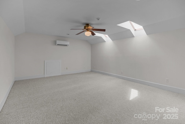 additional living space with ceiling fan, lofted ceiling with skylight, a wall mounted air conditioner, and baseboards