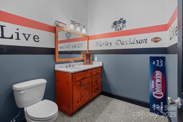 bathroom featuring toilet, speckled floor, and vanity