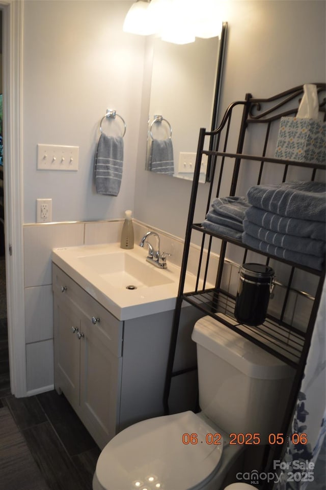 bathroom with vanity, tile walls, and toilet