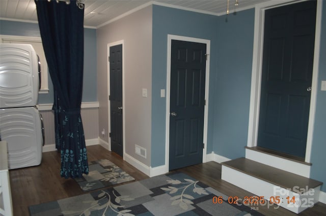 bedroom with crown molding, stacked washer and dryer, and dark hardwood / wood-style floors