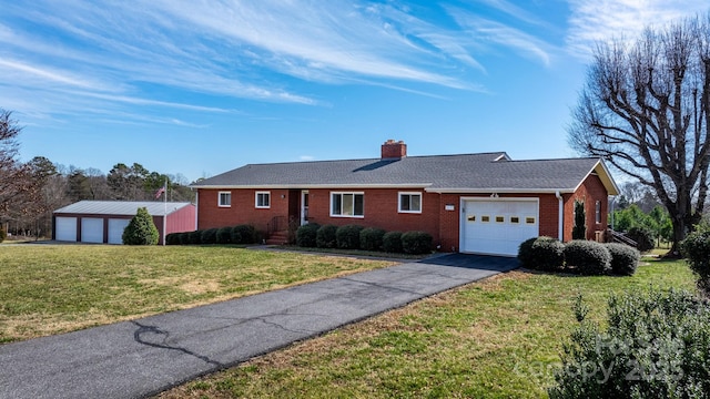 single story home featuring driveway, a chimney, a front lawn, and brick siding