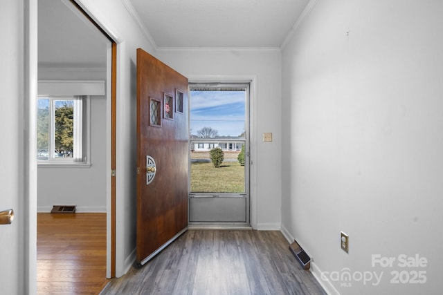 doorway featuring wood finished floors, visible vents, and crown molding