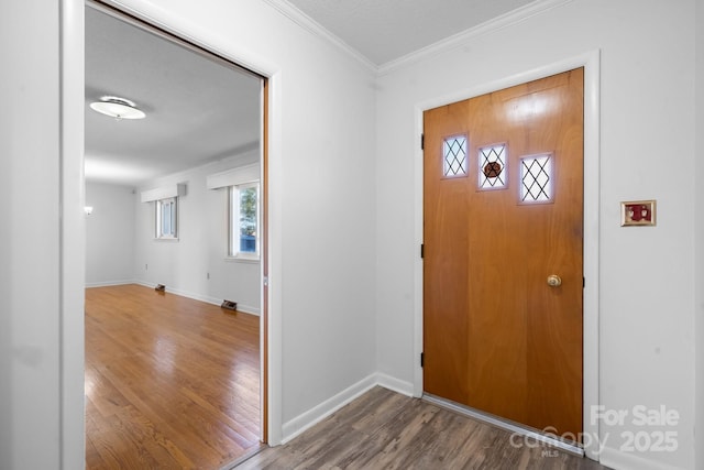 entrance foyer featuring ornamental molding, plenty of natural light, wood finished floors, and baseboards