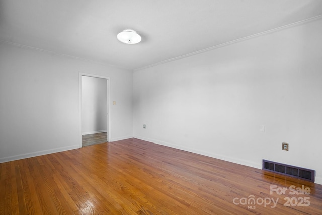 unfurnished room featuring ornamental molding, visible vents, baseboards, and wood finished floors