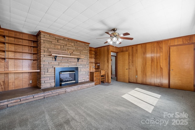 unfurnished living room with carpet, a fireplace, and wooden walls