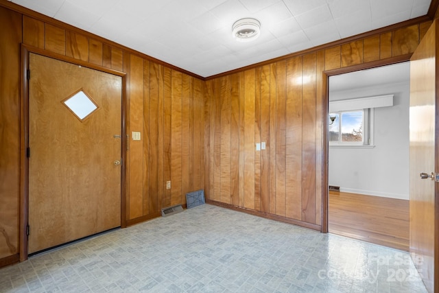 spare room with baseboards, wood walls, and light floors