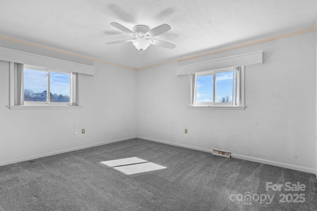 unfurnished room with baseboards, visible vents, ornamental molding, dark colored carpet, and a textured ceiling