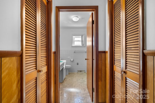 hallway with wainscoting and tile walls