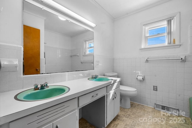 bathroom featuring toilet, double vanity, a sink, and visible vents