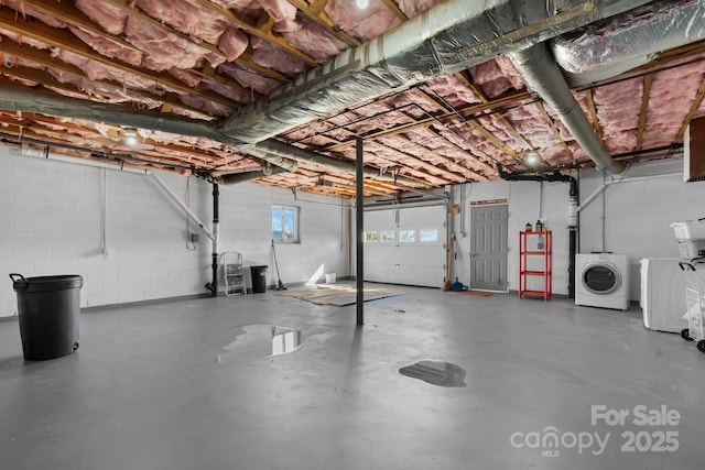 garage featuring concrete block wall and washer and dryer