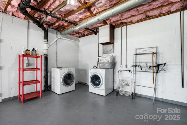 laundry area featuring concrete block wall and washer and clothes dryer