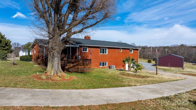 single story home with a front yard, brick siding, a chimney, and a wooden deck