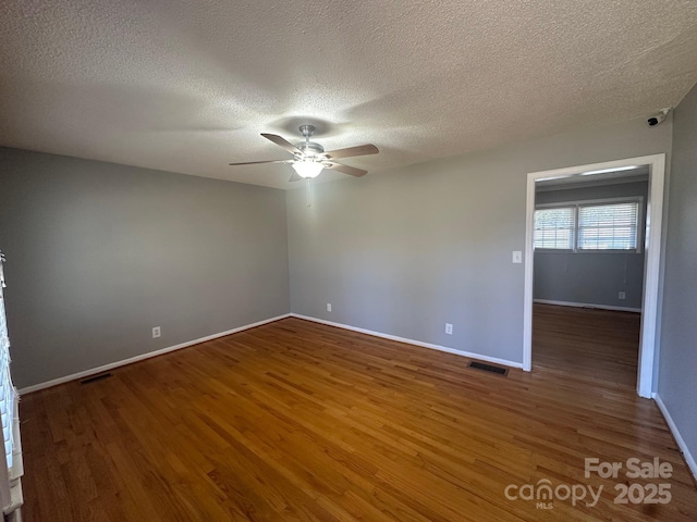 spare room with dark hardwood / wood-style flooring, a textured ceiling, and ceiling fan