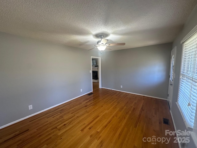 unfurnished room featuring a textured ceiling, wood-type flooring, and ceiling fan