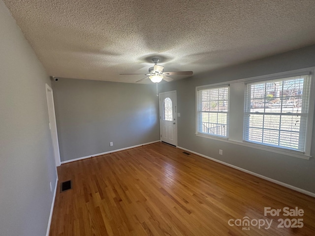 empty room featuring hardwood / wood-style floors, a textured ceiling, and ceiling fan