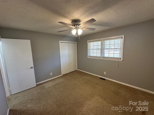 unfurnished bedroom with ceiling fan, a closet, a textured ceiling, and carpet flooring