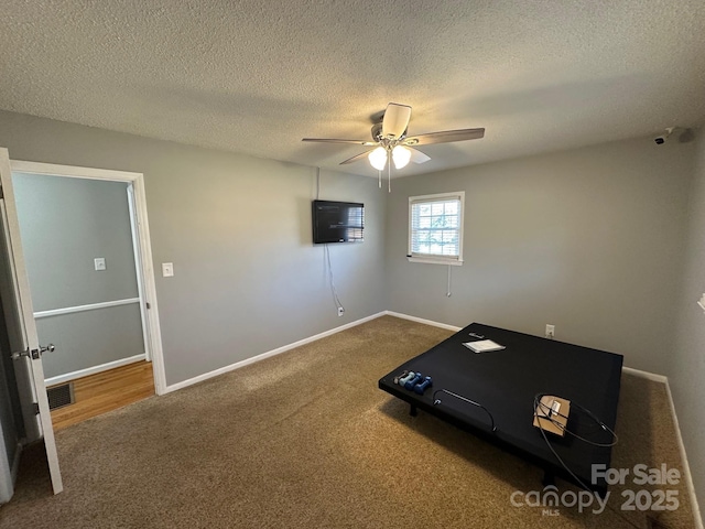 workout area featuring a textured ceiling, ceiling fan, and carpet flooring