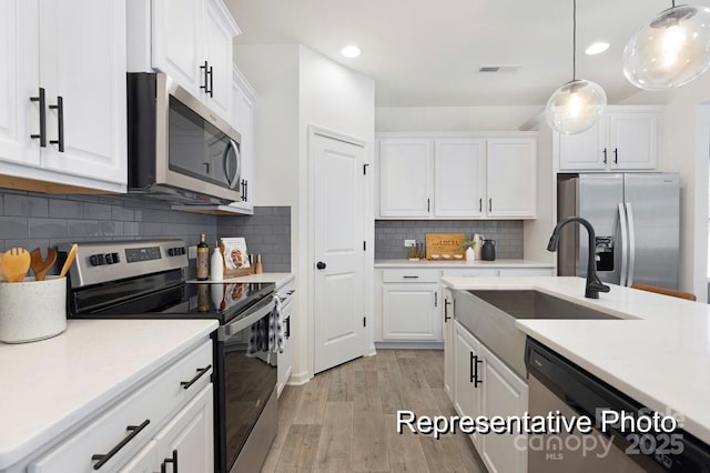 kitchen with pendant lighting, sink, stainless steel appliances, and white cabinets