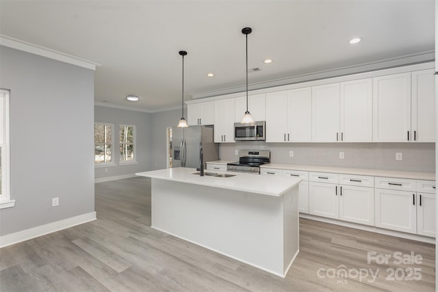 kitchen with sink, appliances with stainless steel finishes, a kitchen island with sink, white cabinetry, and decorative light fixtures