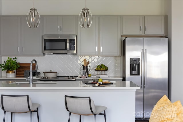 kitchen featuring stainless steel appliances, tasteful backsplash, gray cabinetry, and light countertops