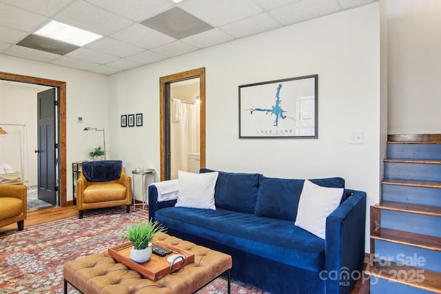 living room with a drop ceiling and wood-type flooring