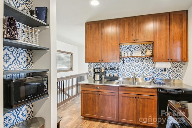 kitchen featuring sink, light hardwood / wood-style flooring, stainless steel counters, black appliances, and decorative backsplash