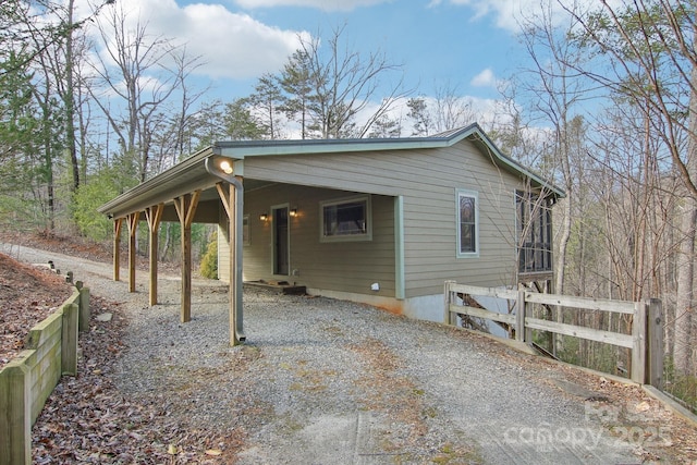 view of home's exterior with gravel driveway and fence