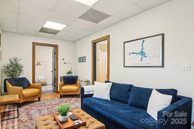 living area with a paneled ceiling and wood finished floors