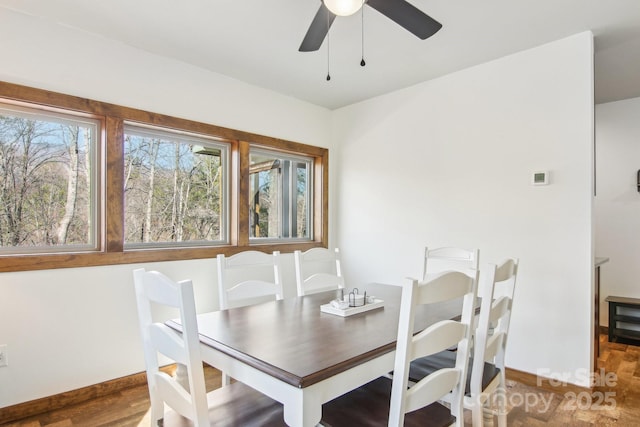 dining space featuring a ceiling fan, baseboards, and wood finished floors